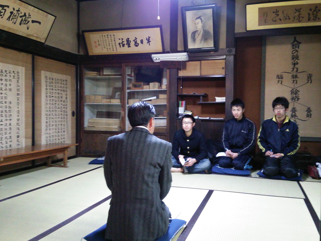 写真の学生の後ろに掛けてあるものは<br>
真ん中が松陰先生の肖像画、<br>
左上は山県有朋書の「半日高堂話」、<br>
右上が陸羯南書の「深く蔵して空の如し」<br>
右の掛け軸は伊東重(伊東家の隣に住んでた医者、養生幼稚園)の<br>
「養生哲学」に関する書です。<br><br> | 授業 時間割 | 東京校ブログ | 大学生・既卒生の就活・起業支援や人間力を鍛える志塾、JVU・日本ベンチャー大學